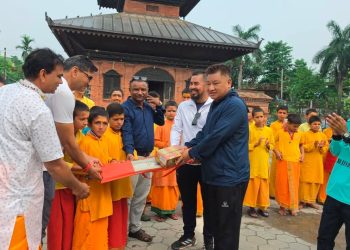 Men in traditional and casual attire handing over cricket equipment to young monks