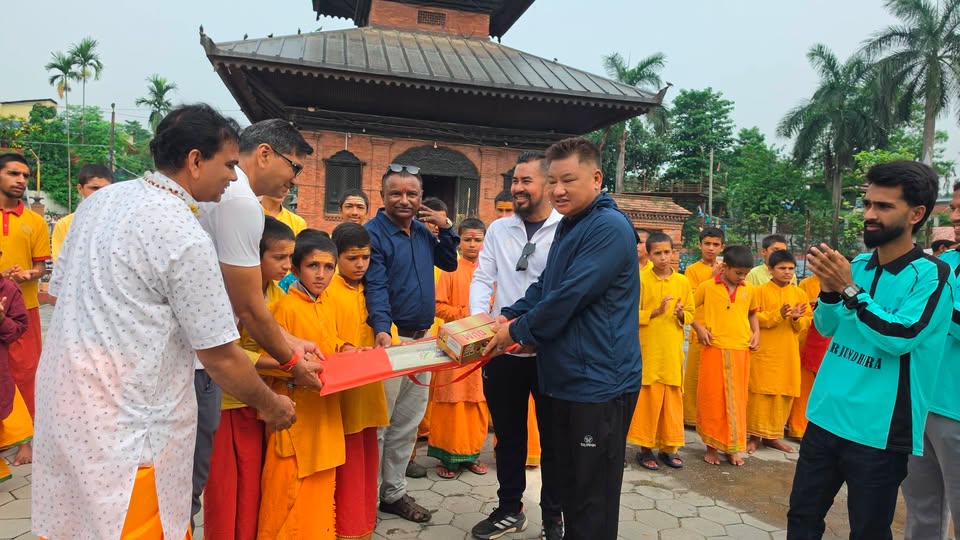 Men in traditional and casual attire handing over cricket equipment to young monks