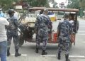 Armed police officers in camouflage uniforms inspecting a loaded cargo vehicle at a border checkpoint, with no specific individuals named in the image.