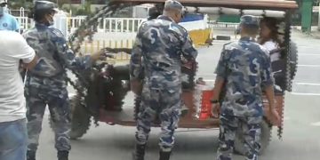 Armed police officers in camouflage uniforms inspecting a loaded cargo vehicle at a border checkpoint, with no specific individuals named in the image.