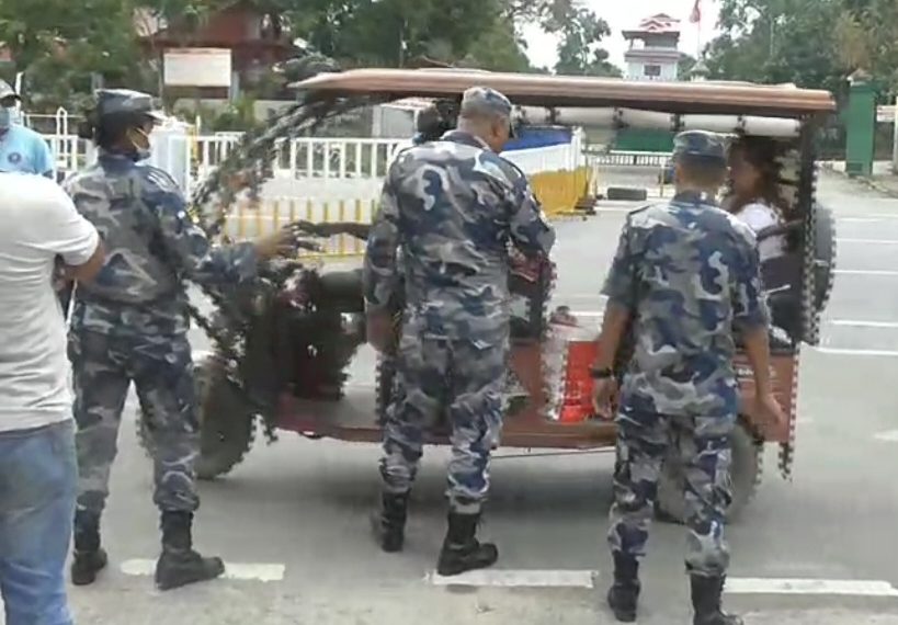 Armed police officers in camouflage uniforms inspecting a loaded cargo vehicle at a border checkpoint, with no specific individuals named in the image.