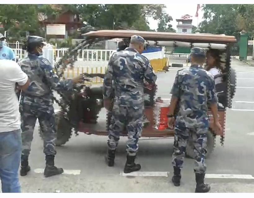 Armed police officers in camouflage uniforms inspecting a loaded cargo vehicle at a border checkpoint, with no specific individuals named in the image.