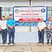 Group photo of officials from various agencies standing in front of a signboard for the Integrated Check Point at Kakarbhitta border crossing. Visible are (from left to right): a security officer in camouflage uniform, officials in plain clothes, and uniformed personnel from Nepal Police, Armed Police Force, and Nepal Customs. They are standing in front of a large sign with Nepali and English text. The scene is set on a concrete pavement outside a building with glass windows.
